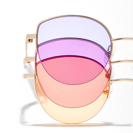 Stacked aviator sunglasses with gradient lenses in purple, red, and orange hues and gold frames.