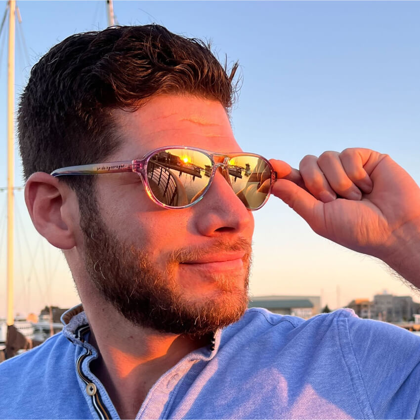 Man wearing reflective, gold-tinted sunglasses under a blue sky.