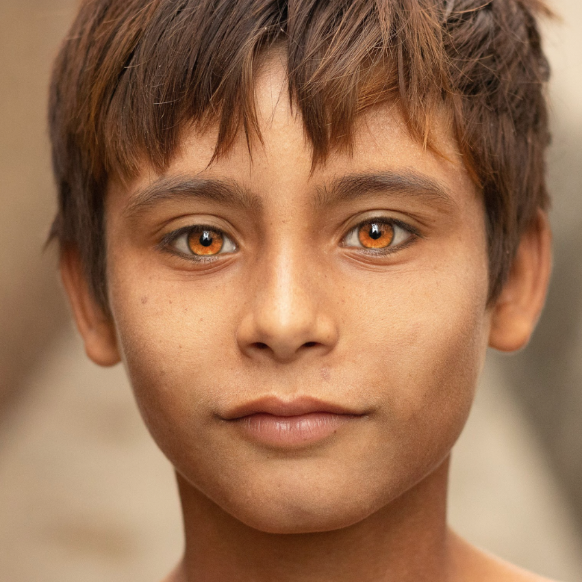Close-up of a child with amber-colored eyes, looking directly at the camera.