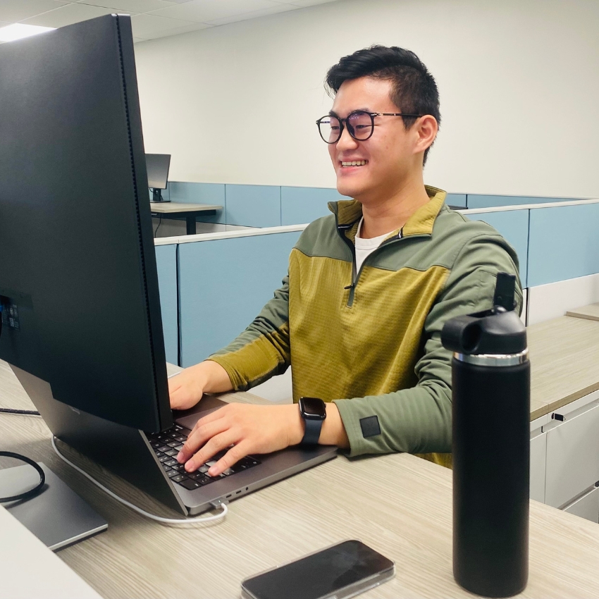 Person using a computer on a desk with a black water bottle and a smartphone nearby.