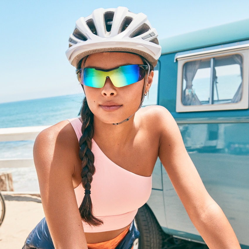 Cyclist wearing a white helmet and reflective, rainbow-tinted sunglasses.