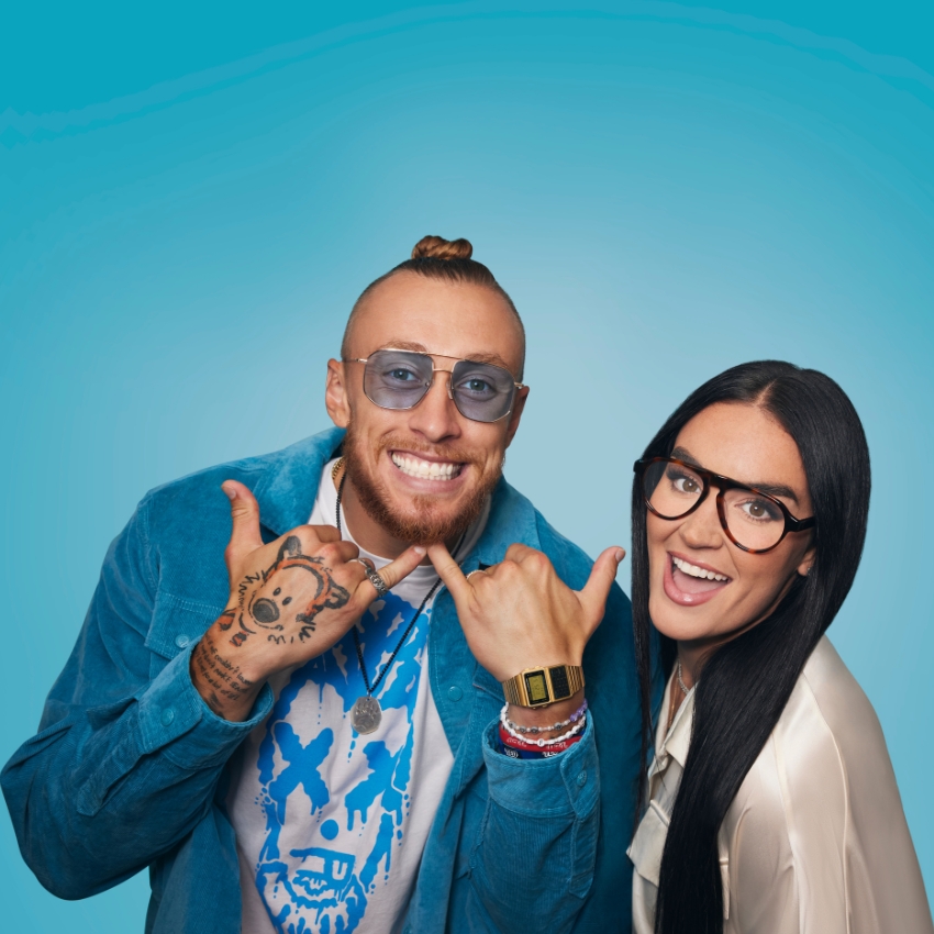 Two people wearing sunglasses and glasses, respectively, smiling and posing against a blue background.