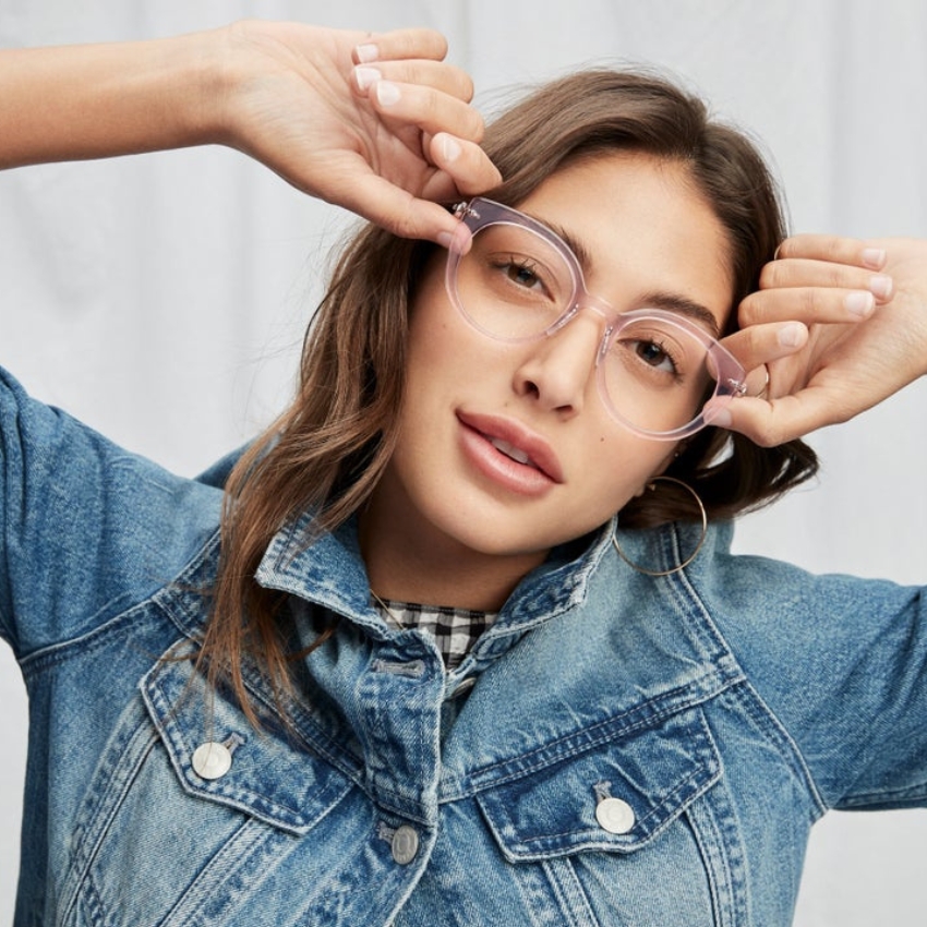 Woman wearing clear-framed glasses and denim jacket.
