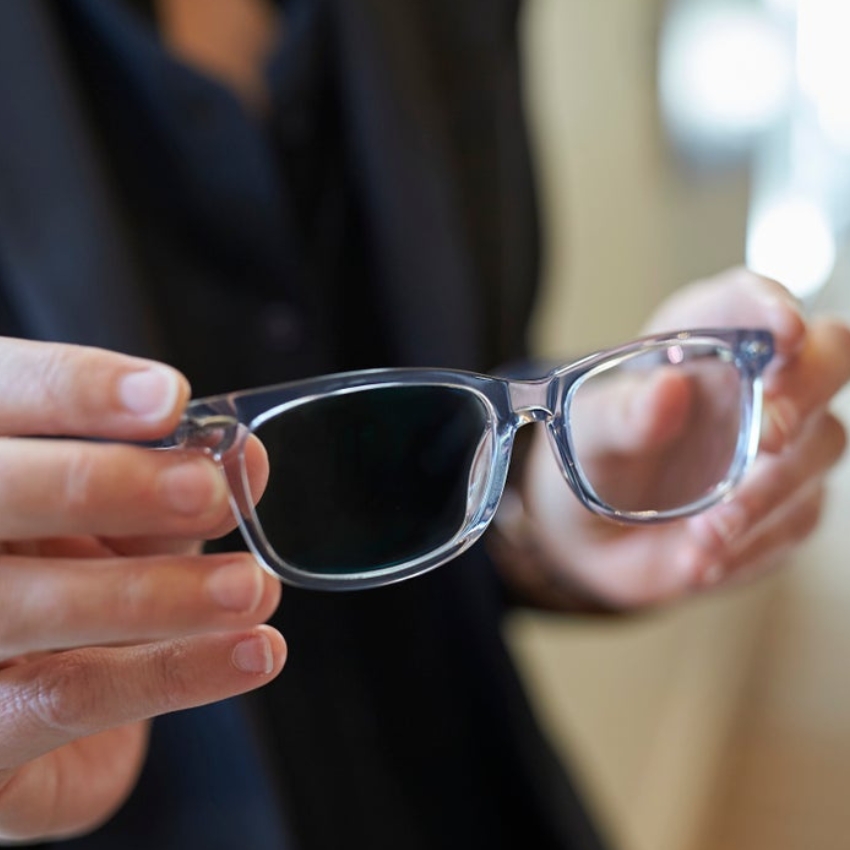 Person holding a pair of clear prescription eyeglasses.