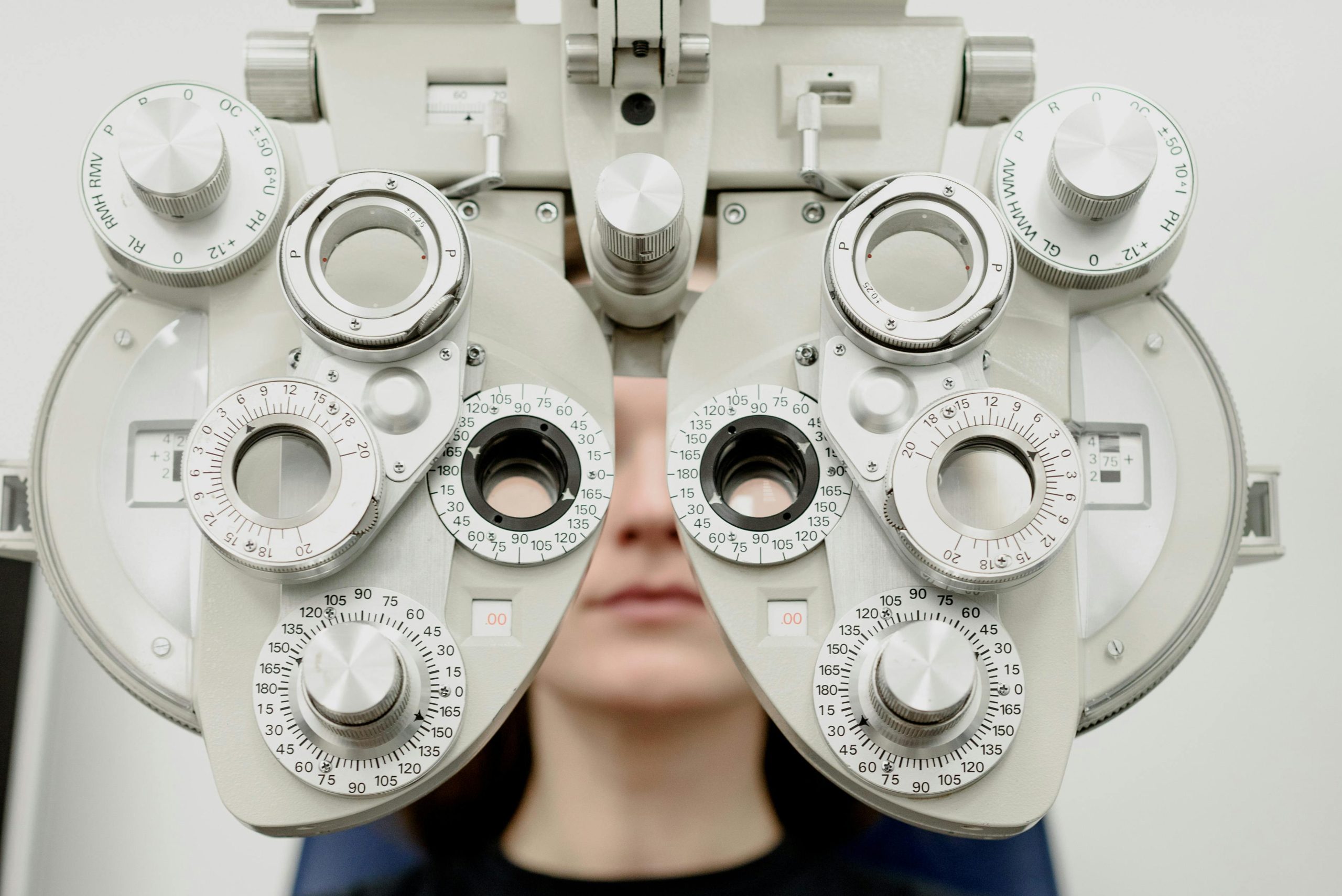 Phoropter used for vision testing, multiple dials and lenses positioned in front of a person's face.